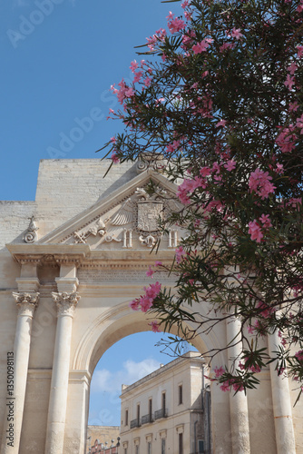 Porta Napoli fragment against the background of blooming pink oleander, Lecce, Italy