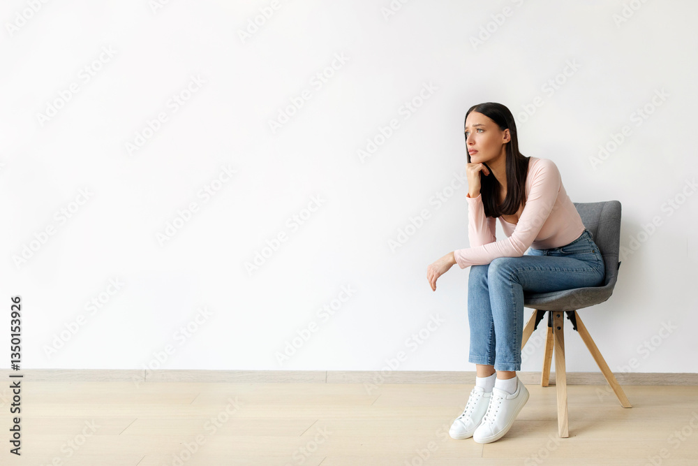 Annoyed sad young lady sitting on chair against white wall, banner with free space. Woman feeling depressed, having bad mood Annoyed sad young lady sitting on chair against white wall, banner with free space. Woman feeling depressed, having bad mood