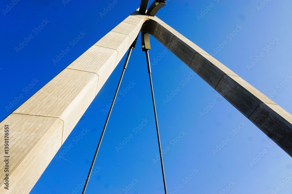 Naklejka premium Emporragender Brückenpfeiler aus Beton mit Kabelseil vor blauem Himmel bei Sonne am Nachmittag im Sommer