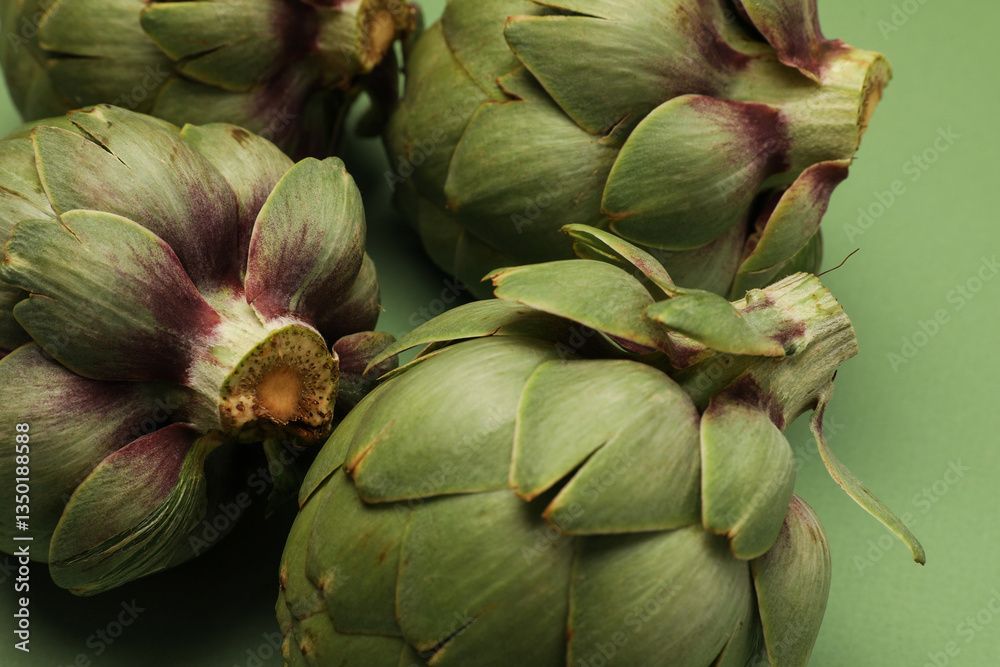 Fototapeta premium Fresh artichoke on green background. Whole green artichokes mockup. Close-up.
