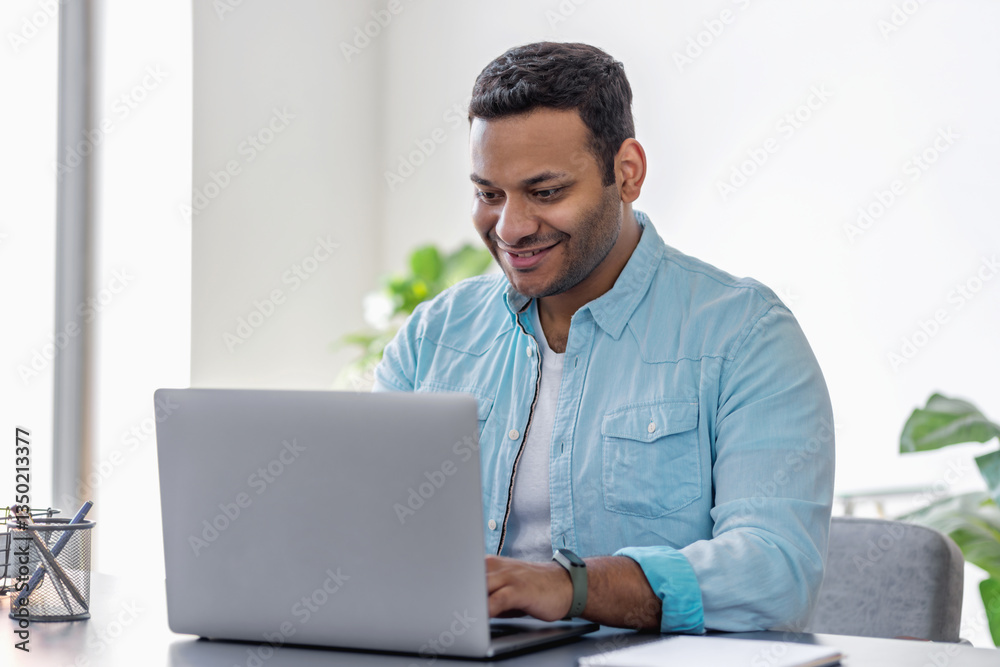 Smiling businessman working on laptop home office