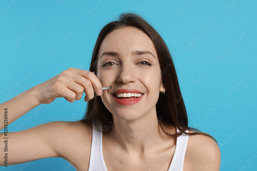 Happy woman plucking her mustache with tweezers on light blue background Happy woman plucking her mustache with tweezers on light blue background