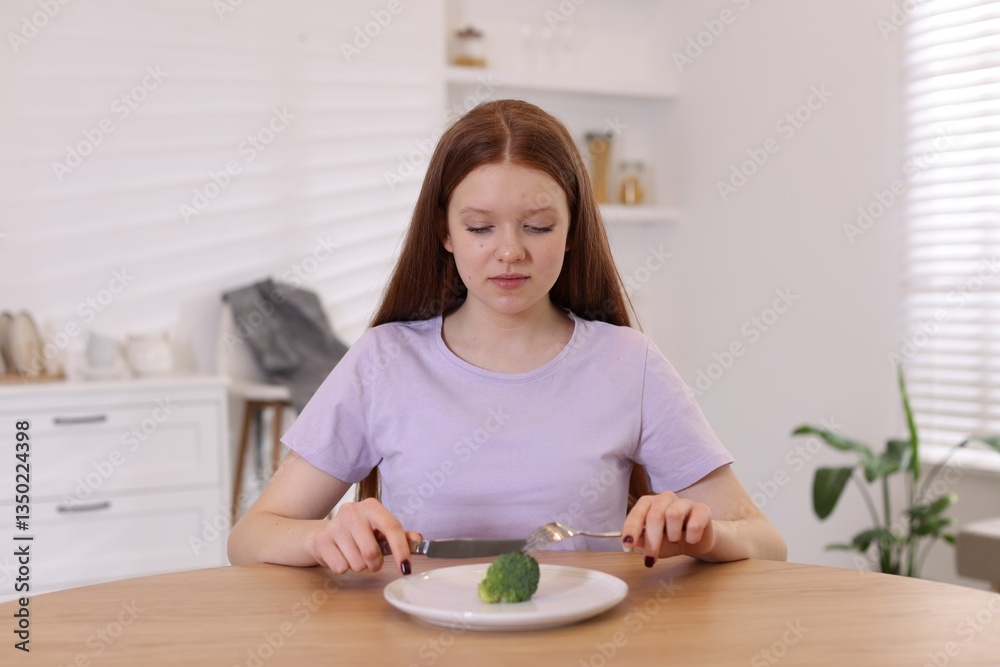 Sad teenage girl with broccoli at wooden table. Eating disorder Sad teenage girl with broccoli at wooden table. Eating disorder