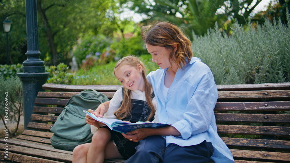 Fototapeta premium Relaxed mom child reading book resting at wooden bench closeup. Cute family