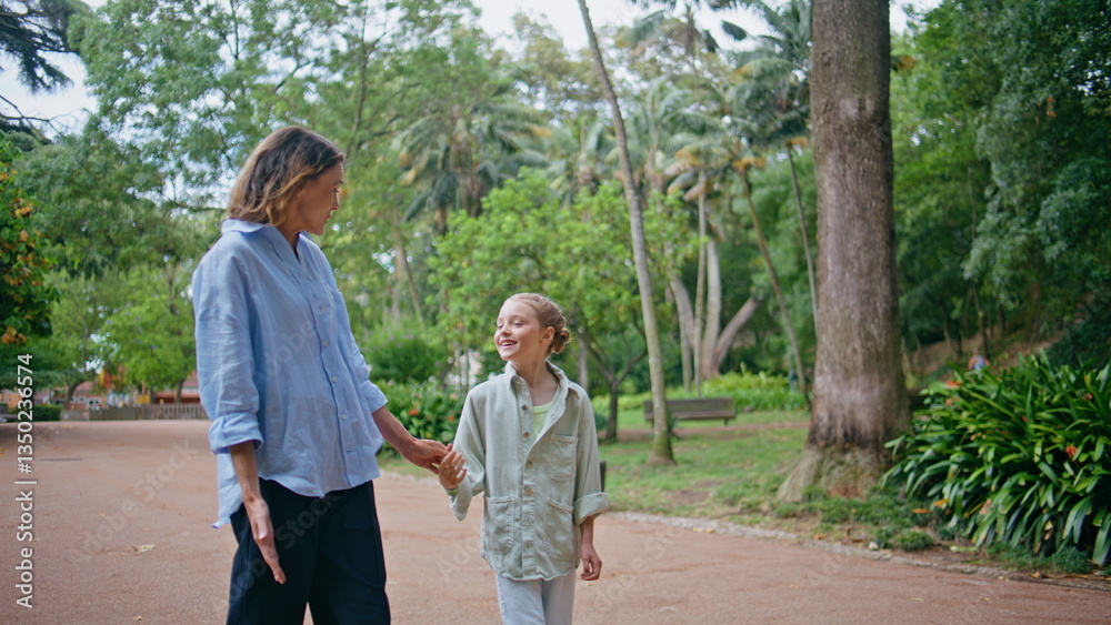 Family walking greenery park. Serene mother strolling together with daughter Family walking greenery park. Serene mother strolling together with daughter