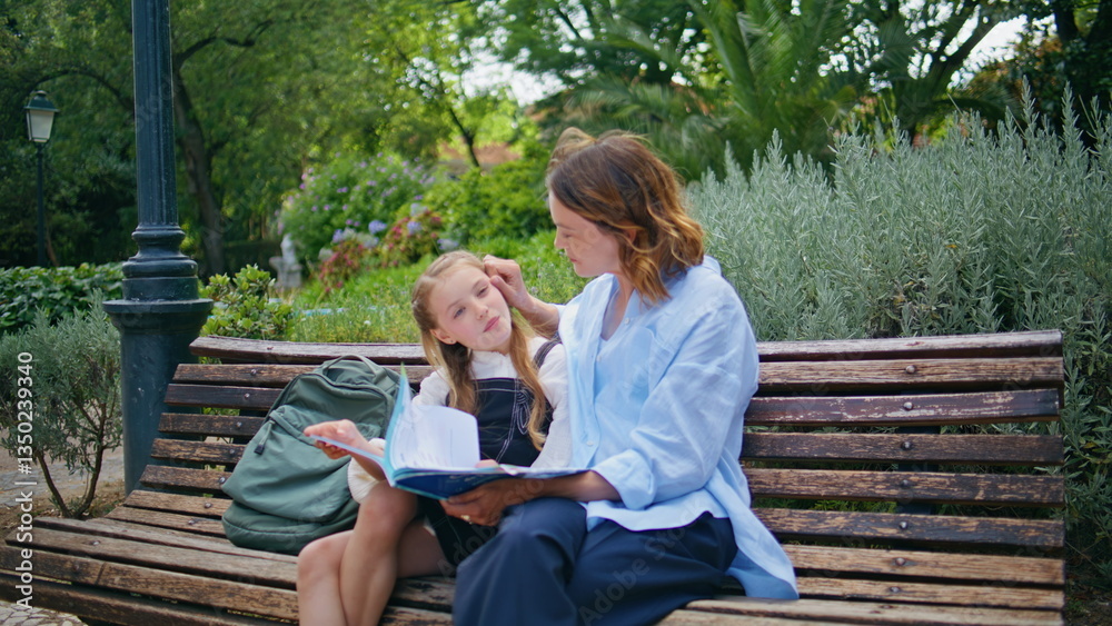 Fototapeta premium Woman girl flipping pages reading fairytale embracing at city garden closeup