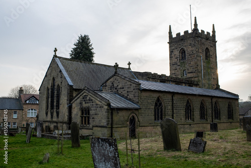 Eham, Chesterfield, United Kingdom - 21 Mar 2025 - Eham Parish church with a cemetery in front of it. The cemetery is full of headstones and the church is surrounded by trees. The sky is cloudy and th