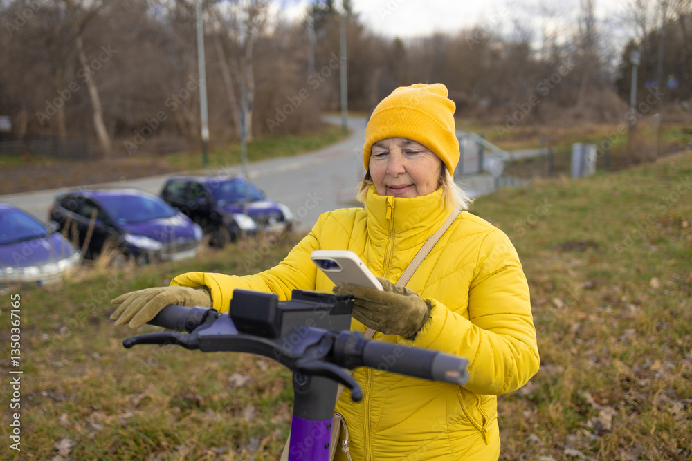 A woman in a yellow jacket and beanie rents an electric scooter using her phone in an urban park. The scene captures the convenience of app-based rental services for eco-friendly transportation.