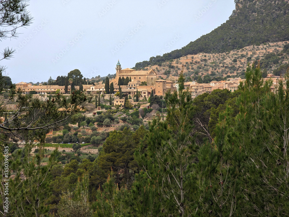 Fototapeta premium Picturesque Valldemossa village view, Serra de Tramuntana mountains, Mallorca, Balearic Islands. Mediterranean buildings, lush greenery, iconic bell tower, traditional terraces, countryside setting.