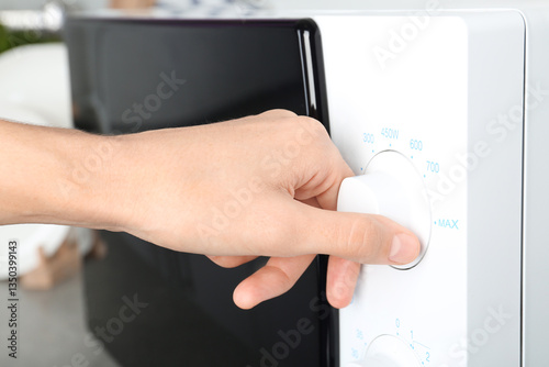 Woman adjusting microwave oven in kitchen, closeup