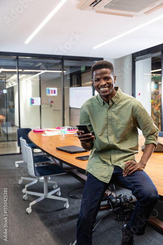 Wallpaper Mural Smiling man using smartphone in modern office, leaning on conference table Torontodigital.ca