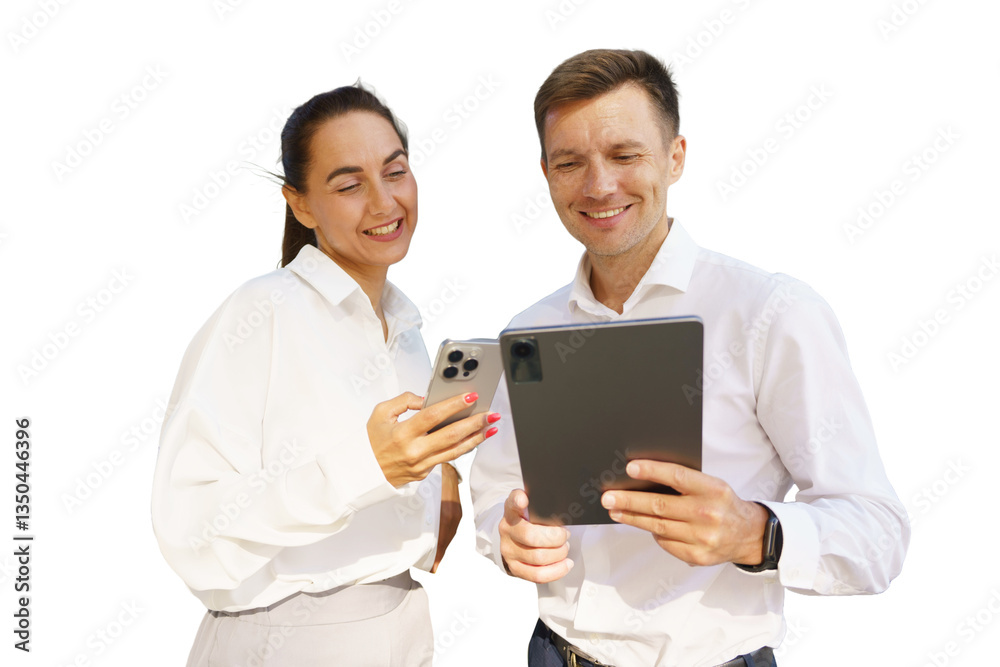 Couple smiling while using smartphone and tablet outdoors during daytime at a bright location Couple smiling while using smartphone and tablet outdoors during daytime at a bright location