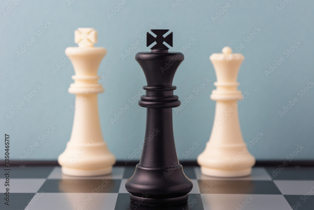 Black king standing between white king and queen on chessboard Black king standing between white king and queen on chessboard