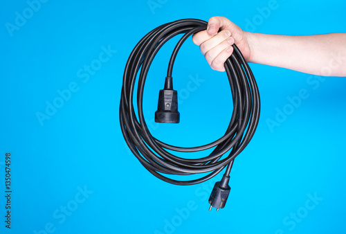 Person holding utility cable with socket and plug.
