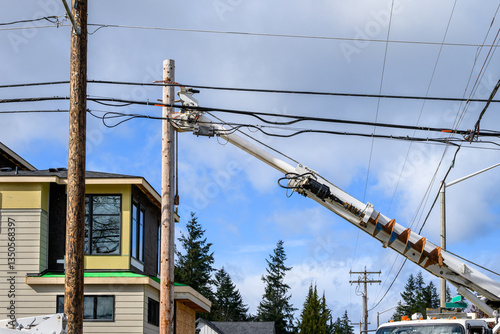 Utility digger derrick truck with pole setting equipment, ready to remove temporary wood powerline pole, infrastructure upgrade supporting new housing development
