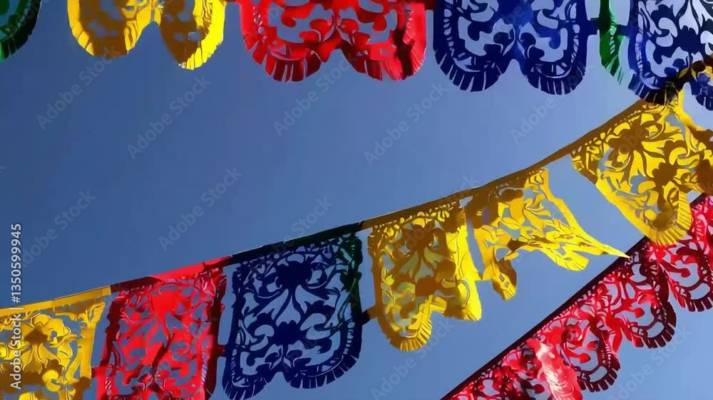 Colorful papel picado banners swaying in the breeze under a clear blue sky