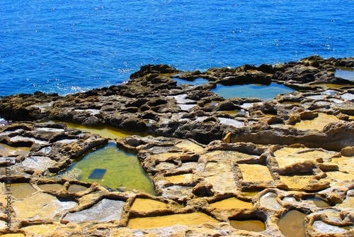 Sea coastline with salt evaporation ponds. Rocky formation on the ocean coast. Coastline with water, travel photography.