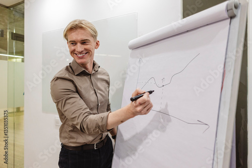 Smiling businessman drawing growing graph on flip chart during presentation