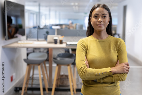 Cuadro en lienzo Confident businesswoman standing with arms crossed in modern office workspace, c