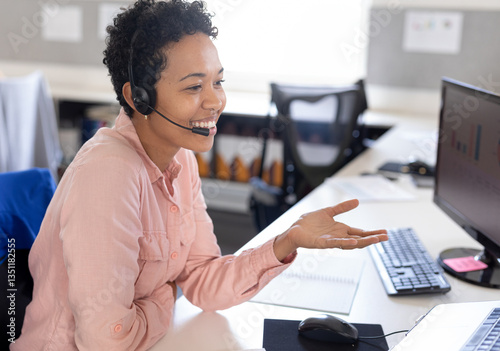 African American woman using headset smiling while working at office desk
