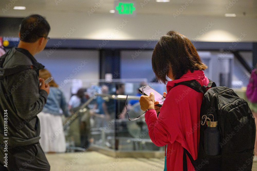 Couple checking smartphone at the airport departure area. USA.