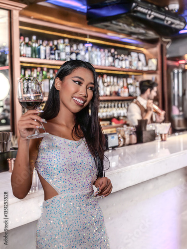 A glamorous woman in a sparkling sequin dress holding a glass of red wine at an elegant bar. She smiles confidently, radiating sophistication and charm. The luxurious bar setting