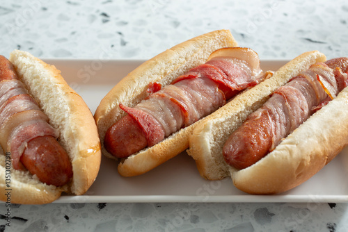 A view of some bacon-wrapped hot dogs on a tray.