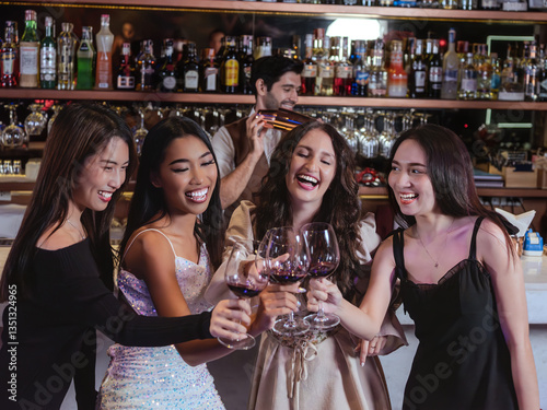 Obraz na płótnie elegant women group clinking wine glasses in a stylish bar, sharing a joyful moment. The background features a professional bartender preparing drinks, with shelves of premium liquor bottles w salonie