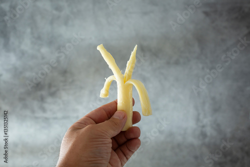 A view of a hand holding a piece of string cheese.