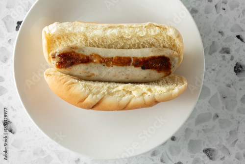 A top down view of a bratwurst hot dog, on a plate.