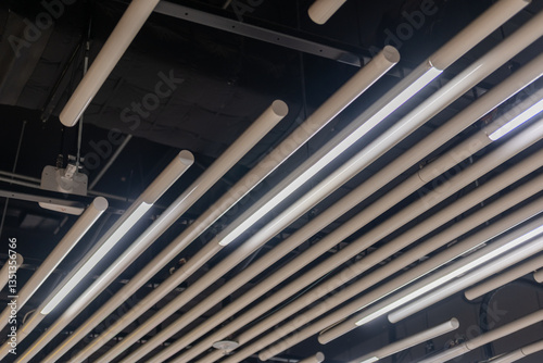 Suspended tube ceiling decoration with integrated linear lighting for diffused illumination, ideal for public space