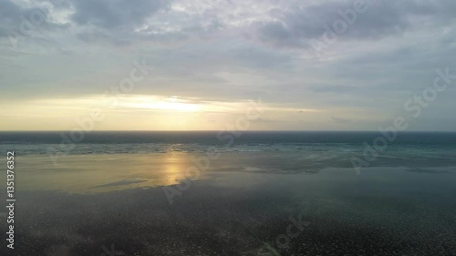 Wallpaper Mural A steady aerial shot hovering above calm waters near BM Beach, Puerto Princesa. The sun rises gently above the ocean, with warm light reflecting off the sea and a clear horizon in view. Torontodigital.ca