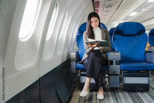 Woman Reading on Airplane: A composed woman engrossed in a book, seated comfortably on an airplane, illuminated by natural light through the windows, signifying travel and leisure.