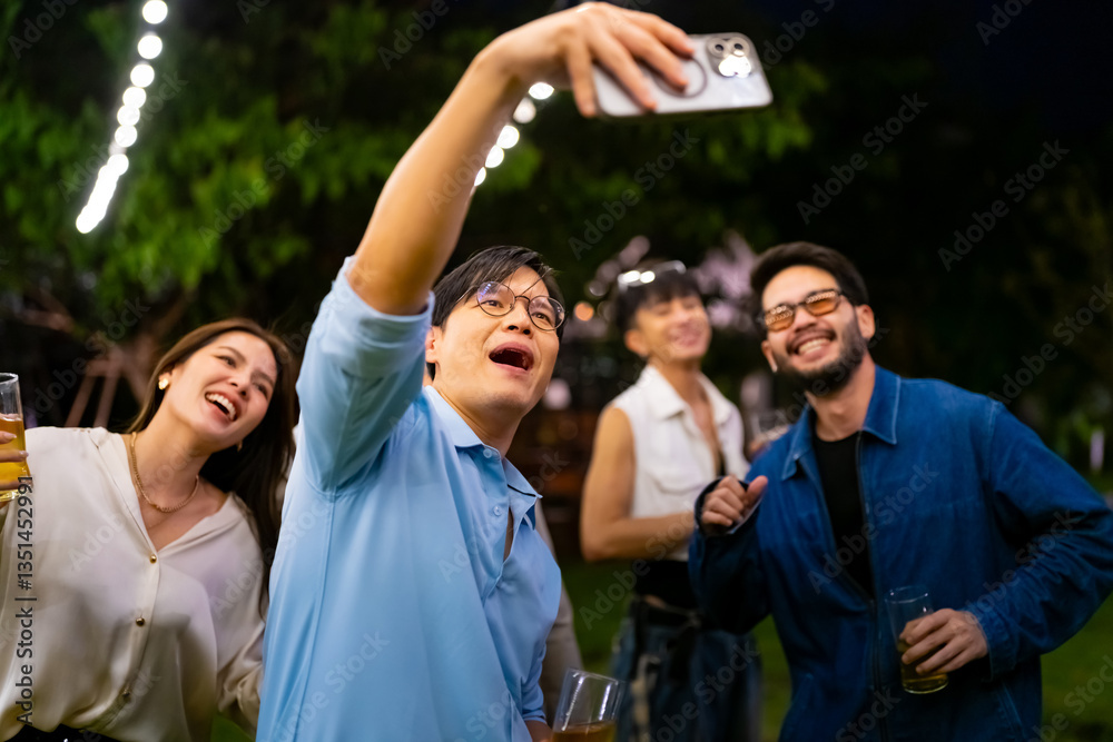 Obraz premium Group of Happy Asian millennial people friends enjoy and fun celebration reunion meeting using mobile phone taking picture together at dinner party in the garden at restaurant on holiday vacation.