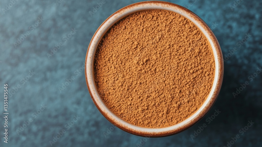 Fragrant Cinnamon Powder in Bowl on Blue Surface Fragrant Cinnamon Powder in Bowl on Blue Surface