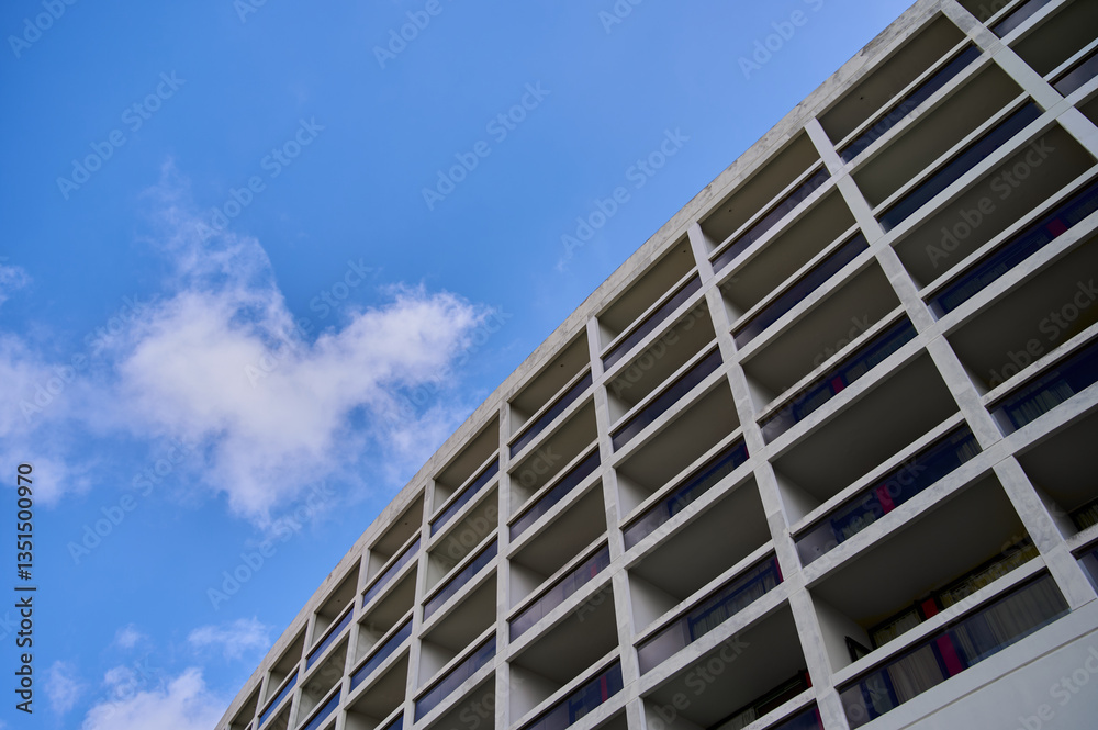 Hotel structure with minimalist design features bright clouds and blue sky, showcasing modern architecture. Hotel structure with minimalist design features bright clouds and blue sky, showcasing modern architecture.