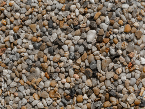 Rough Floor Made Of Small Stones Of Various Sizes. Stone Wall Composed Of Tiny White, Brown And Black Stones Embedded In Cement.