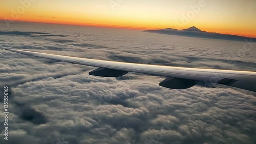 AIRCRAFT FLYING OVER A SEA OF CLOUDS AT SUNSET