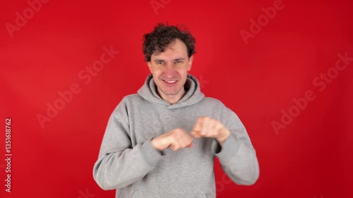 Happy man in casual making dab arms gesture on blank red studio background, funny white guy dabbing moving in internet meme pose celebrating victory having fun, dance school or triumph concept