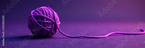 Round purple yarn ball, loose end trails downward , coil, knitting