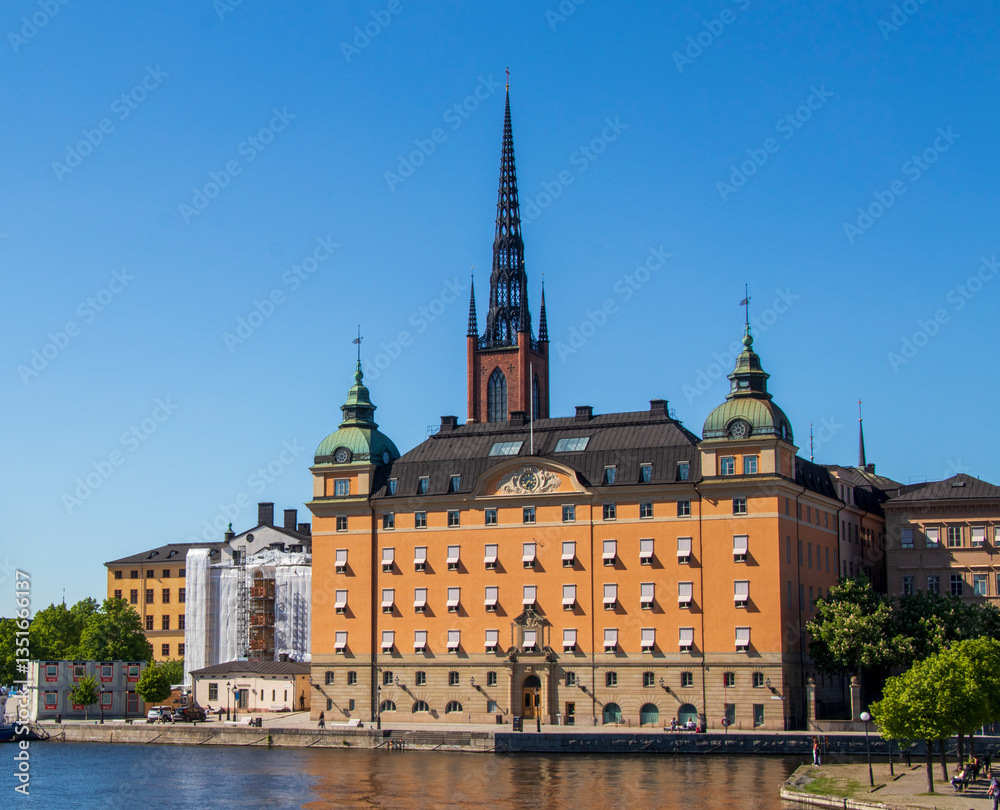 Fototapeta premium Scenic view of Riddarholmen Church and surrounding historic buildings in Stockholm, Sweden, on a sunny day with clear blue sky.