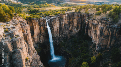 A stunning aerial view of a waterfall nestled within a rugged canyon