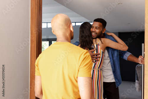 Diverse friends greeting each other warmly at home, sharing joyful hugs and smiles