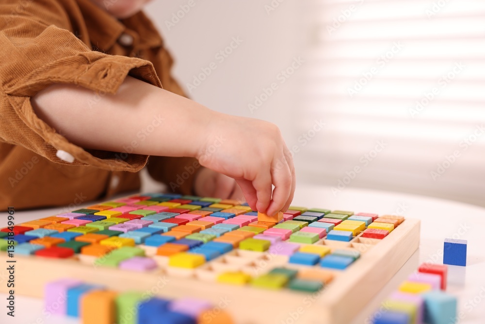 Fototapeta premium Motor skills development. Little boy playing with Times table tray indoors, closeup