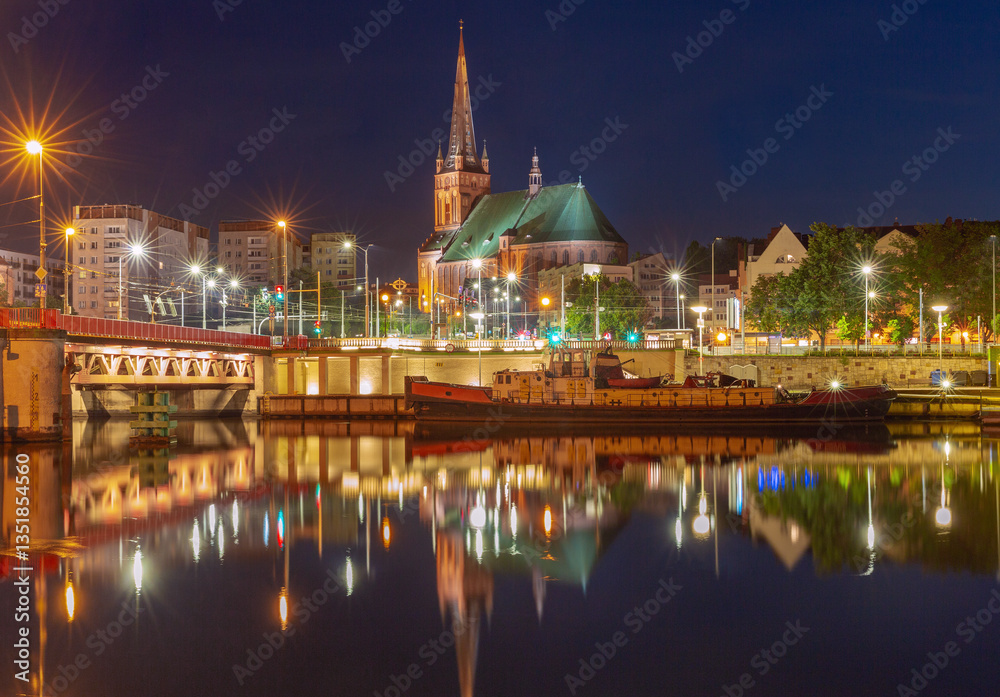 St James Cathedral in Szczecin Poland illuminated at night with city lights and reflections in the Oder River