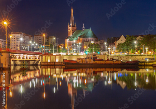 St James Cathedral in Szczecin Poland illuminated at night with city lights and reflections in the Oder River
