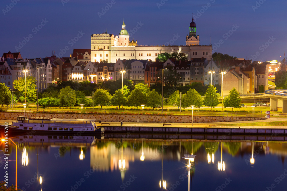 Oder River waterfront in Szczecin Poland with illuminated buildings and docked boats before sunrise