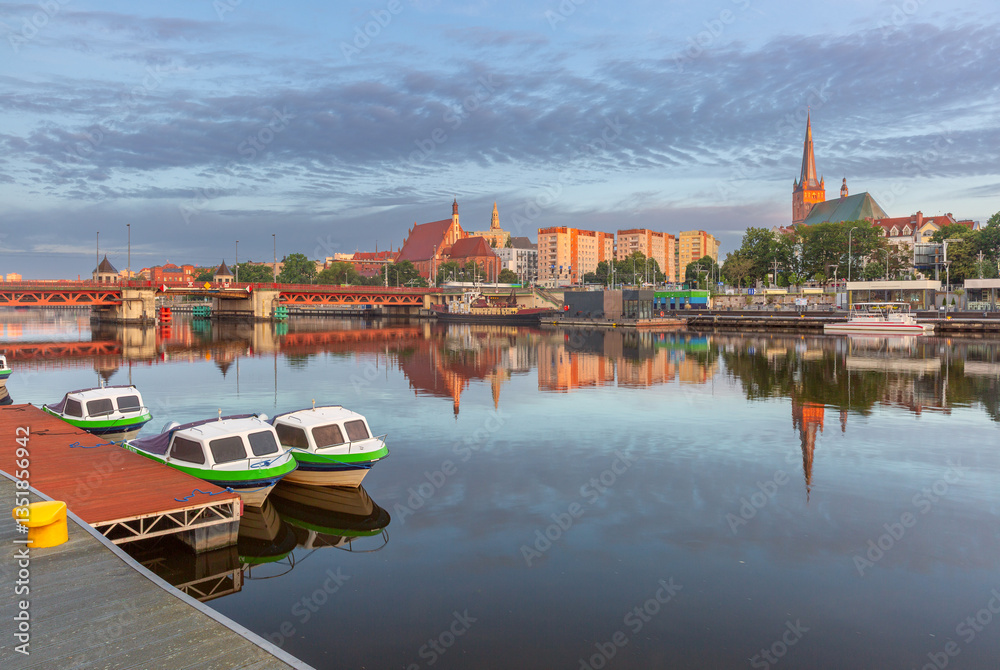 Oder River waterfront in Szczecin Poland with illuminated buildings and docked boats before sunrise