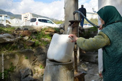 alte Frau füllt Wasser aus Pumpe in Eimer