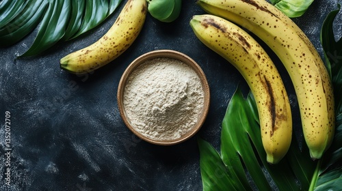 Banana powder in bowl with fresh bananas and tropical leaves